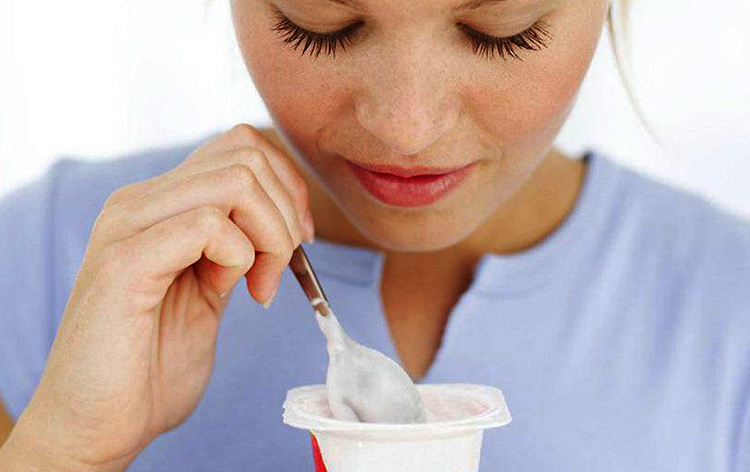 Девушка кушает йогурт